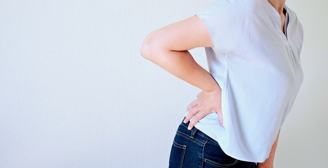脊椎分離症の痛みで腰を押さえる女性の画像