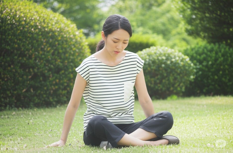 夏バテによる胃腸の不調で、屋外でぐったりとしている若い日本人女性。
