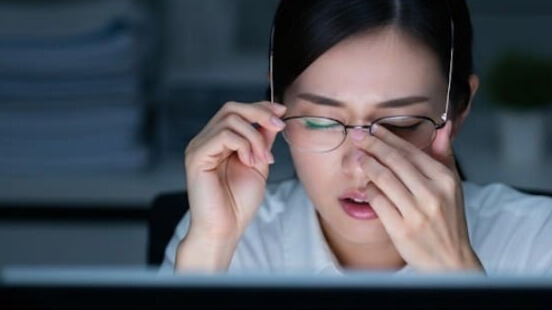 寝不足と眼精疲労で、目の奥の痛みに悩む女性。