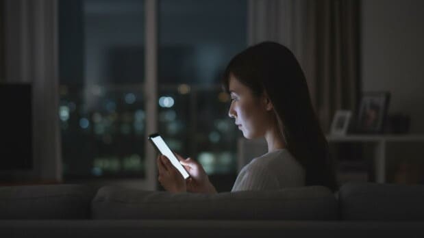 スマートフォンで逆流性食道炎と甘いものについて調べ、悩んでいる女性。