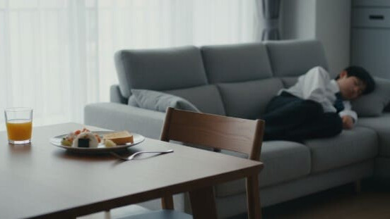 朝ごはんが食べられず、ソファでぐったりしている起立性調節障害の子供。