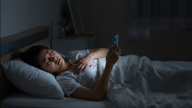 逆流性食道炎で眠れず、夜中に胸元を押さえて苦しむ女性。