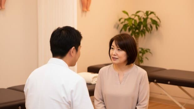 浜崎鍼灸整骨院の院長が、患者に寄り添い、親身になって問診をしている風景。