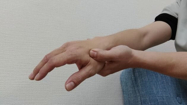 手のツボ（合谷）を押している様子、過敏性腸症候群の痛み緩和のためのセルフケア