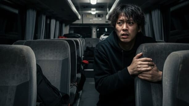 窓のない閉鎖的な空間（ロケバス内部）で緊張した表情を浮かべる若い日本のアイドル。逃げ場のない環境が脳に与えるストレスを表現した画像